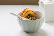 Bol avec granola et tranches de fruits sur table blanche — Photo de stock