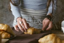 Manos femeninas rebanando croissant - foto de stock