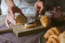 Frauenhände putzen Marmelade auf Croissant — Stockfoto