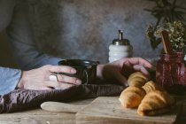 Mãos femininas segurando copo e tomando croissant — Fotografia de Stock