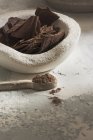 Nature morte de bol en pierre avec chocolat noir et cuillère de poudre de coacoa — Photo de stock