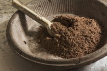 Natura morta di ciotola di pietra con cacao fondente in polvere e cucchiaio di legno — Foto stock
