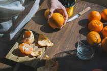 Mulher mão descascamento maduro doce tangerina — Fotografia de Stock