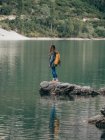 Zaino in spalla femminile su pietra nel lago — Foto stock