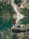 Жінка з рюкзаком на камені в озері — стокове фото