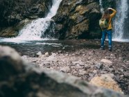 Frau mit Rucksack erkundet Wasserfall — Stockfoto
