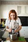 Cheerful woman adds flour — Stock Photo