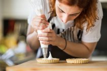 Женщина намазывает сливки на пироги — стоковое фото