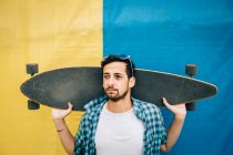 Homme barbu tenant skateboard — Photo de stock