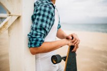 Чоловік стоїть зі скейтбордом на березі — стокове фото