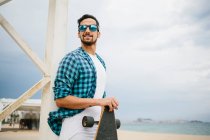 Homme avec planche à roulettes à la plage — Photo de stock