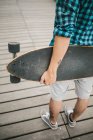 Человек с татуировками держит скейтборд — стоковое фото