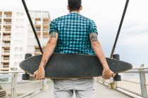 Man with tattoos holding skateboard — Stock Photo
