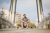 Uomo seduto su skateboard su strada vuota — Foto stock