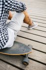 Homme tatoué assis sur skateboard — Photo de stock