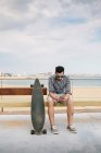 Mann in der Nähe von Skateboard und Smartphone. — Stockfoto
