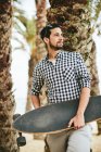 Junger lächelnder Mann mit Skateboard — Stockfoto