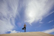 Женщина практикует йогу на песках — стоковое фото