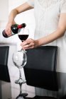 Frau schenkt Rotwein ein — Stockfoto