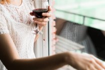 Donna con bicchiere da vino alla finestra — Foto stock