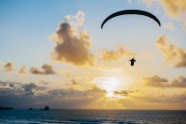 Silhouette flying on parachute over sea — Stock Photo