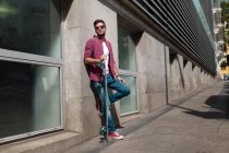 Trendy man posing with longboard on street — Stock Photo