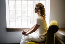 Woman in white dress at window — Stock Photo