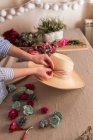 Crop person decorating hat with flowers — Stock Photo