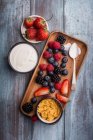 Berries, yogurt and cereals in a wooden tray — Stock Photo