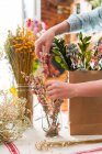 Persona de la cosecha componiendo flores en bolsa - foto de stock