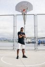 Homme noir confiant posant sur le terrain de basket — Photo de stock
