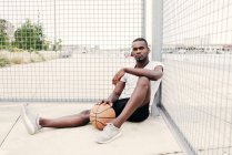 Homme confiant assis avec le basket — Photo de stock
