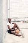 Hombre seguro sentado con baloncesto - foto de stock