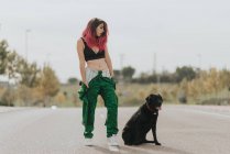 Девушка с черной собакой позирует на дороге — стоковое фото