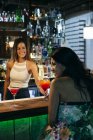 Smiling woman bartender giving cocktail — Stock Photo