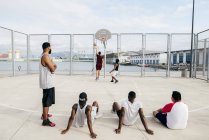 Hombres viendo a otros jugando baloncesto - foto de stock