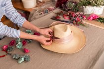 Crop person decorating hat with flowers — Stock Photo
