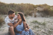 Fröhliches Paar sitzt am Strand — Stockfoto