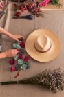 Crop personne décoration chapeau avec des fleurs — Photo de stock
