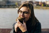 Frau beißt in Cupcake — Stockfoto