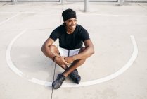 Чоловік сидить на баскетбольному майданчику — стокове фото