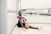 Selbstbewusster Mann sitzt beim Basketball — Stockfoto