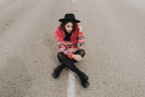 Girl in hat sitting on roadway — Stock Photo