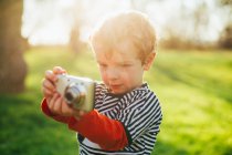 Малюк в сільській місцевості робить фотографію з компактною камерою — стокове фото