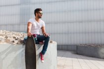 Trendiger Mann mit Skateboard posiert — Stockfoto