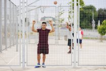 Jovem esportivo posando atrás da cerca — Fotografia de Stock