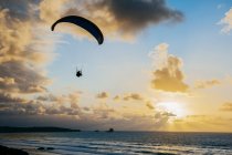 Silhouette fliegt am Fallschirm über dem Meer — Stockfoto