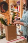 Женщина кладет цветы в бумажный пакет — стоковое фото