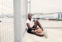 Confident man sitting with basketball — Stock Photo