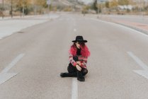 Menina sentada na estrada com pernas cruzadas — Fotografia de Stock